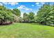 Picture of a wide green backyard with a wooden fence, mature trees and bushes at 1410 Shadow Ct, Zionsville, IN 46077