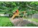 Backyard view of a wooden playground, swing set, and slide surrounded by mature trees in a well-maintained yard at 1410 Shadow Ct, Zionsville, IN 46077