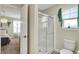 This is a bright bathroom with a glass-enclosed shower, a toilet, and plants by the window at 15023 Glenmoor Cir, Carmel, IN 46033