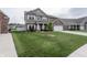 Charming two-story home with brown siding, brick accents, white trim, an attached two-car garage, and a large lawn at 1661 Devonshire Ave, Avon, IN 46123
