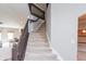 Carpeted staircase with dark wood railing leading to the upper level of the home at 1661 Devonshire Ave, Avon, IN 46123