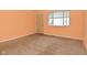 Bedroom with tan carpet, peach walls, a window, and a wooden door at 1802 Sugar Grove Ave, Indianapolis, IN 46202