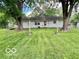 Back exterior view of a home with mature trees, a well maintained lawn, and a white privacy fence at 1834 Chandler Ln, Columbus, IN 47203