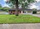 Charming single-story home featuring a red door, attached garage, and a lush green lawn at 1834 Chandler Ln, Columbus, IN 47203