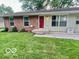 Charming home featuring a red door, brick accents, and well-maintained landscaping at 1834 Chandler Ln, Columbus, IN 47203