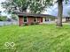A well-maintained single story home with a lush green lawn and mature shade tree in the front yard at 1834 Chandler Ln, Columbus, IN 47203