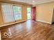 Bright living room with a large window, wood laminate flooring, and a red front door at 1834 Chandler Ln, Columbus, IN 47203