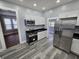 Modern kitchen features stainless steel appliances, white cabinetry, and wood-look vinyl flooring at 24 N Randolph St, Indianapolis, IN 46201