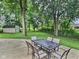 Backyard patio with dining table and chairs, surrounded by mature trees and lush greenery at 2741 Fairlawn Dr, Columbus, IN 47203