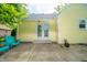 Back of yellow home featuring a patio, glass door, and seating with beautiful green foliage around at 311 Northshore Blvd, Anderson, IN 46011