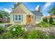 Charming yellow home featuring stone accents, a welcoming wooden front door, and lush landscaping at 311 Northshore Blvd, Anderson, IN 46011