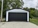 Spacious detached garage with a large black door, set against a backdrop of lush greenery at 317 W Pierson St, Greenfield, IN 46140