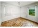 A bedroom shows windows overlooking green outdoor scenery, a hardwood floor, and white walls at 3615 N Dequincy St, Indianapolis, IN 46218