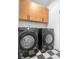 A laundry room with front-load black washer and dryer and wood cabinets at 420 Monon Wy Dr, Carmel, IN 46032