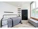 Comfortable bedroom featuring a metal bed frame, exposed brick, large window, and bench seat at 430 N Park Ave # 211, Indianapolis, IN 46202
