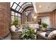 Bright sunroom with brick walls, arched windows, cozy seating, and potted plants at 430 N Park Ave # 211, Indianapolis, IN 46202