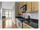 Kitchen features stainless steel appliances, black countertops, light wood cabinets, and hardwood floors at 450 E Ohio St # Apt 305, Indianapolis, IN 46204