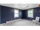 Simple carpeted bedroom featuring paneled blue walls, two windows, and a white chair at 4817 N 150 W, Anderson, IN 46011
