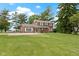 Two-story brick home with an expansive lawn, mature trees, and red front door offers classic charm and curb appeal at 4817 N 150 W, Anderson, IN 46011