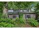 Two-story gray brick home featuring multi-pane windows, a green roof, and abundant landscaping for enhanced privacy at 5035 Boulevard Pl, Indianapolis, IN 46208