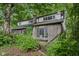 Two-story gray brick home with a multi-pane windows and a green roof nearly obscured by lush greenery at 5035 Boulevard Pl, Indianapolis, IN 46208