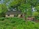Home exterior with a stone facade, a greenhouse addition, and a landscape featuring abundant foliage at 5035 Boulevard Pl, Indianapolis, IN 46208