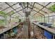 Interior of a run-down glass greenhouse with an aluminum frame filled with metal shelving and debris covered floor at 5035 Boulevard Pl, Indianapolis, IN 46208