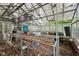 Indoor shot of a run-down greenhouse with leaf covered metal shelving and a glass roof at 5035 Boulevard Pl, Indianapolis, IN 46208