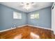 A bright bedroom features hardwood floors, two windows, blue walls, and a ceiling fan at 5092 S 50 W, Anderson, IN 46013
