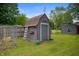 A gray shed sits in a grassy back yard, next to a weathered fence at 5092 S 50 W, Anderson, IN 46013