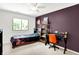 Bedroom with purple accent wall, desk, and a window overlooking a green yard at 5953 Deer Hollow Ct, Pittsboro, IN 46167
