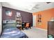 Colorful bedroom featuring purple and orange walls, desk, and built-in shelving at 5953 Deer Hollow Ct, Pittsboro, IN 46167