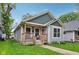 Quaint bungalow with a inviting covered front porch and lush green lawn, perfect for relaxation at 617 N Dearborn St, Indianapolis, IN 46201