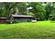 View of the gray house, green lawn, and tank in the backyard surrounded by lush greenery and mature trees at 6190 Red Day Rd, Martinsville, IN 46151
