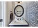 Stylish half bathroom with a round mirror, patterned wallpaper, and elegant fixtures at 644 Ridge Gate Dr, Brownsburg, IN 46112