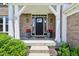 Inviting front porch with brick columns, black front door, and potted flowers at 644 Ridge Gate Dr, Brownsburg, IN 46112
