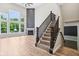 Bright living room featuring a fireplace, large windows, wood-look floors, and a staircase at 644 Ridge Gate Dr, Brownsburg, IN 46112