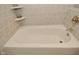 A white bathtub with tile surround and shelving at 6550 Sunset Ln, Indianapolis, IN 46260