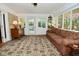 Bright sunroom featuring a comfortable sofa, large windows, and access to the outdoors at 6550 Sunset Ln, Indianapolis, IN 46260