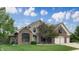 Charming two-story home with brick and stone exterior, well-kept lawn, and mature trees, creating a welcoming facade at 8338 Hunters Meadow Way, Indianapolis, IN 46259