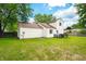 Back exterior view of the home featuring a wooden deck, lush green grass, and mature trees at 8416 Buckingham Dr, Columbus, IN 47201