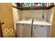 Convenient laundry room featuring a washer and dryer set with shelving above for storage at 865 Countryside Ln, Columbus, IN 47201