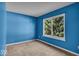 Cozy bedroom with a bright blue accent wall and a large window overlooking mature trees at 8908 Sunningdale Blvd, Indianapolis, IN 46234