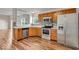 Kitchen featuring stainless steel appliances, wood cabinetry, tile backsplash and wood-look flooring at 8908 Sunningdale Blvd, Indianapolis, IN 46234