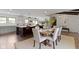 Open-concept dining area with a modern wooden table set, flowing into the kitchen area with a large island and barstools at 10502 E Lakeshore Dr, Carmel, IN 46033