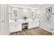 Bright bathroom featuring dual sinks with decorative mirrors, white cabinets, and hardwood floors at 10965 Fairway Ridge Ln, Fishers, IN 46037