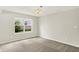 Neutral bedroom with light gray walls, carpet, ceiling light, and a large window with a view to the green outdoors at 11437 High Grass Dr, Indianapolis, IN 46235