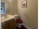 Compact powder room featuring a single sink vanity, toilet with dark maroon cover, and neutral decor at 11621 Coastal Dr, Indianapolis, IN 46229