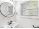 Bathroom with sleek sink, round mirror, and window at 1425 N Grant Ave, Indianapolis, IN 46201