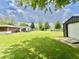 Large, green backyard with a patio, shed, detached garage and tree line at 1579 Crest Dr, Shelbyville, IN 46176